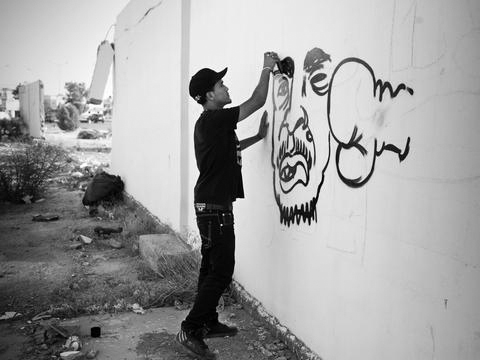 Franco Pagetti VII Photo In a Land of Silence - Janine di Giovanni GREY, Radwan, 22? posing for porttrait in front of hisgraffiti in Benghazi, Libya June 23, 2011<br /> Radwan is deaf-mute.<br /> During the Kadaffi time, he had been imprisoned and<br /> tortured, and though tough and street smart.